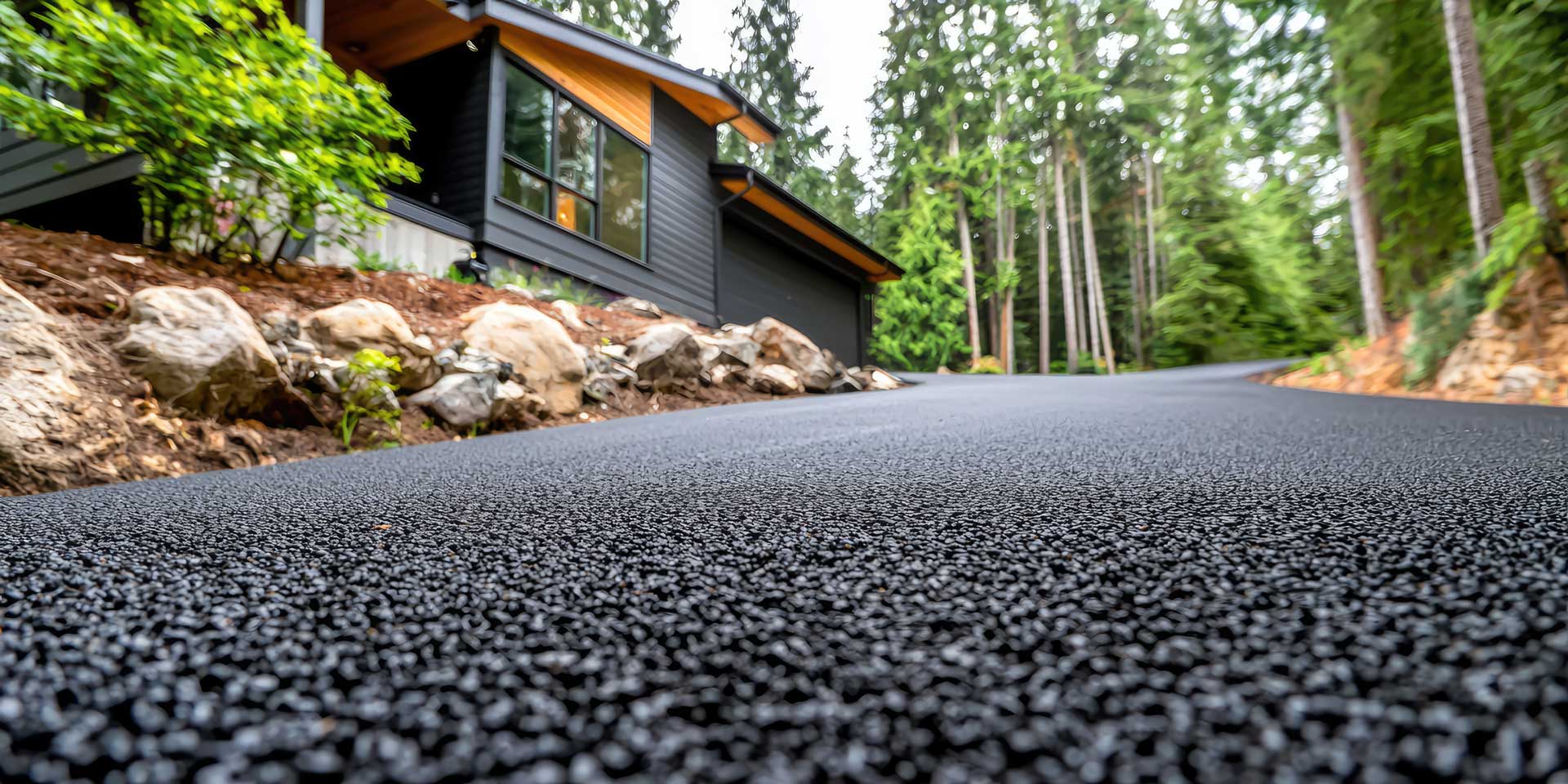 Entrée résidentielle en asphalte fraîchement pavée devant une maison au style contemporain, entourée de forêt à Drummondville